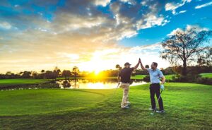 Two golfers give each other high fives while on the course 