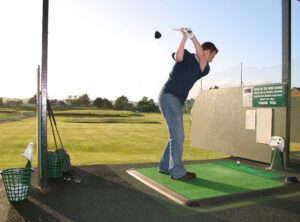 Golfer winding up to swing at a driving range 