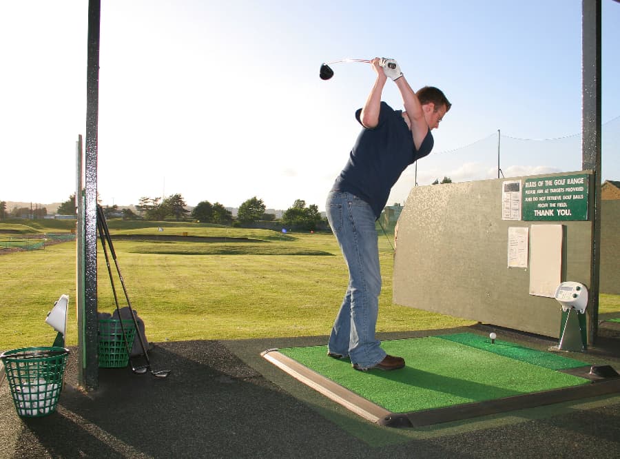 Golfer winding up to swing at a driving range