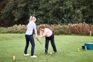Golf coach teaching golfer how to hold club